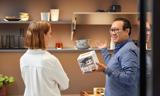 Um especialista Blum mostra a uma mulher no showroom como os produtos Blum podem ser valorizados com displays.