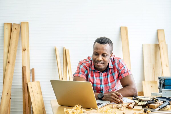 Man looking at a laptop in a woodworking shop
